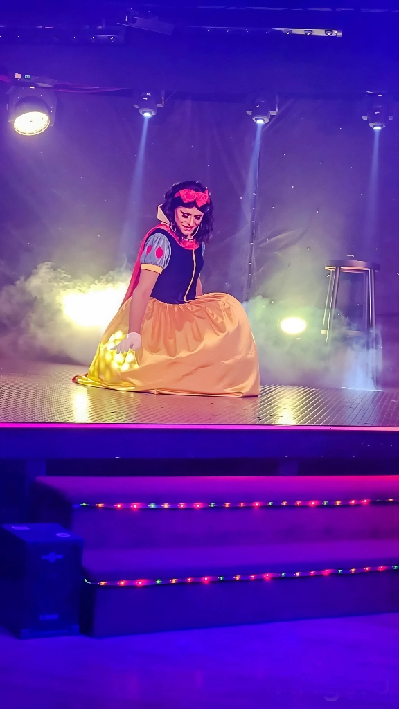 Miss Caline en costume Blanche-Neige sur scène éclairée, spectacle transformiste
